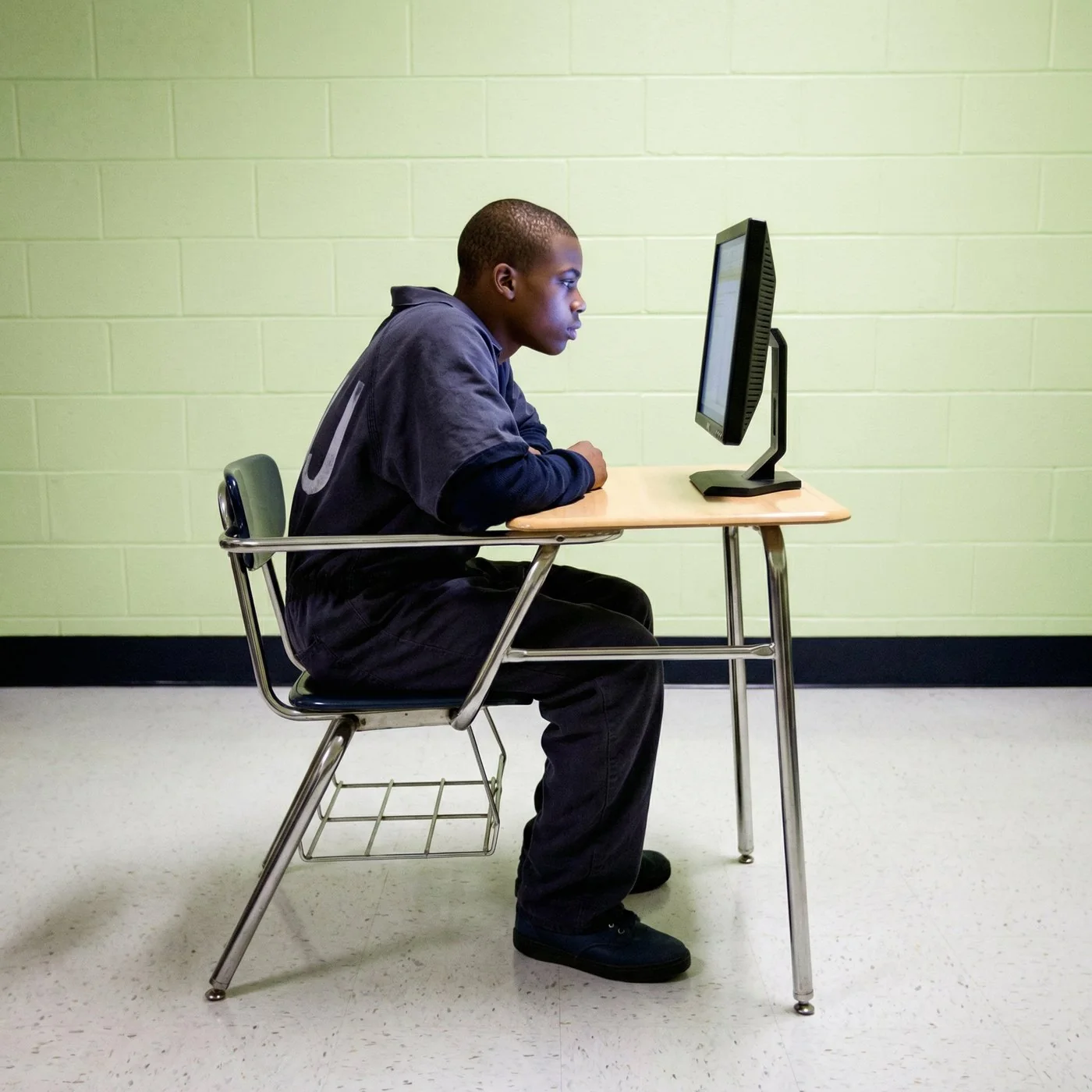 A young man works at a computer at a desk inside a facility classroom