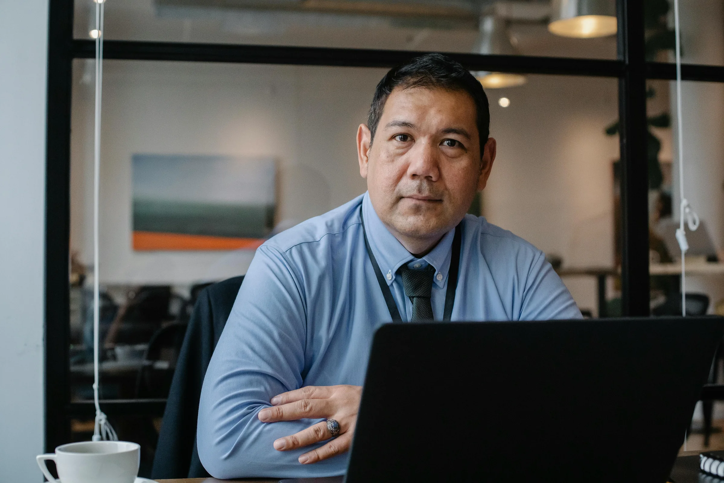 A man in a shirt and tie works at a laptop in an office