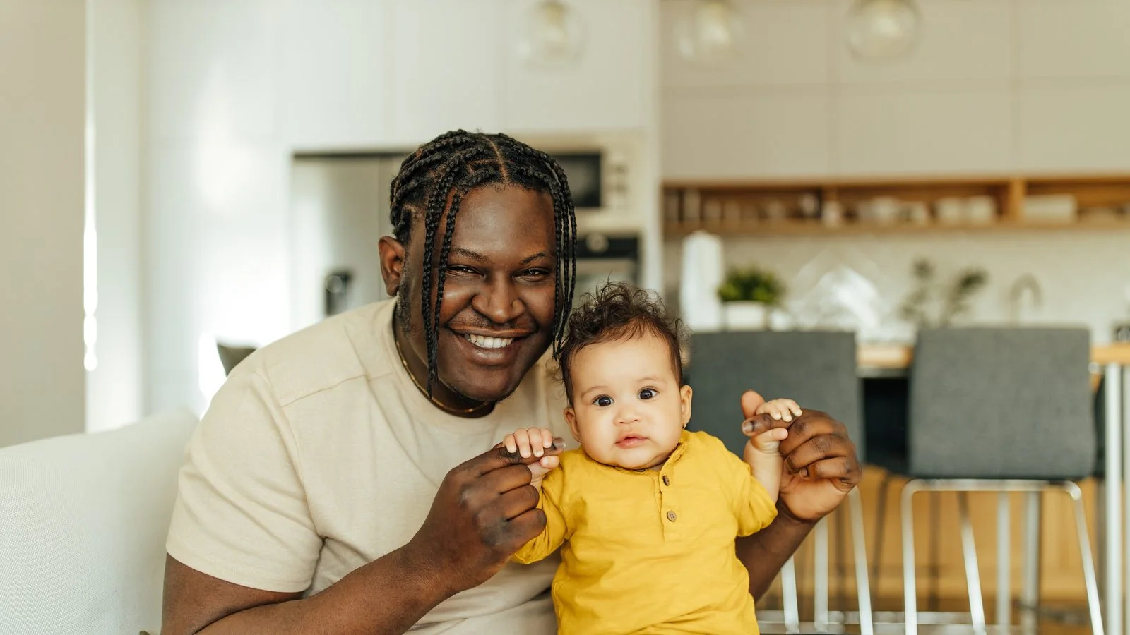 A father holds his baby daughter in a sunny kitchen