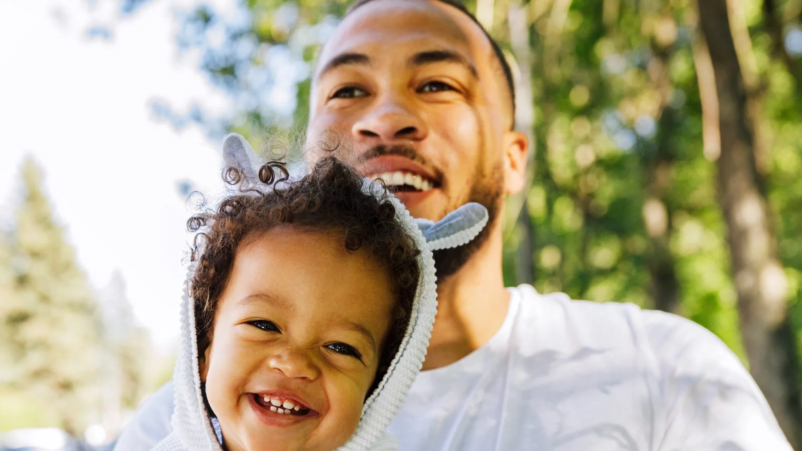 A father carries his laughing toddler outdoors