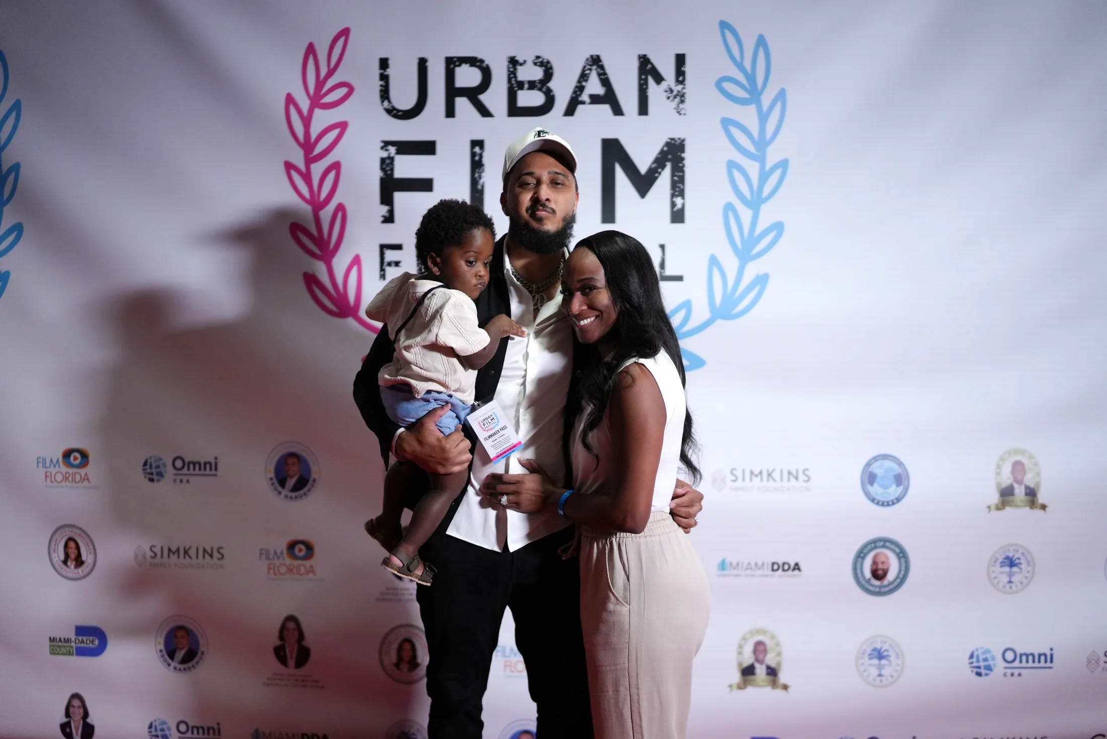 Ronnie Lillard with a filmmaker pass, holding his son beside Christine at the Urban Film Festival in Miami