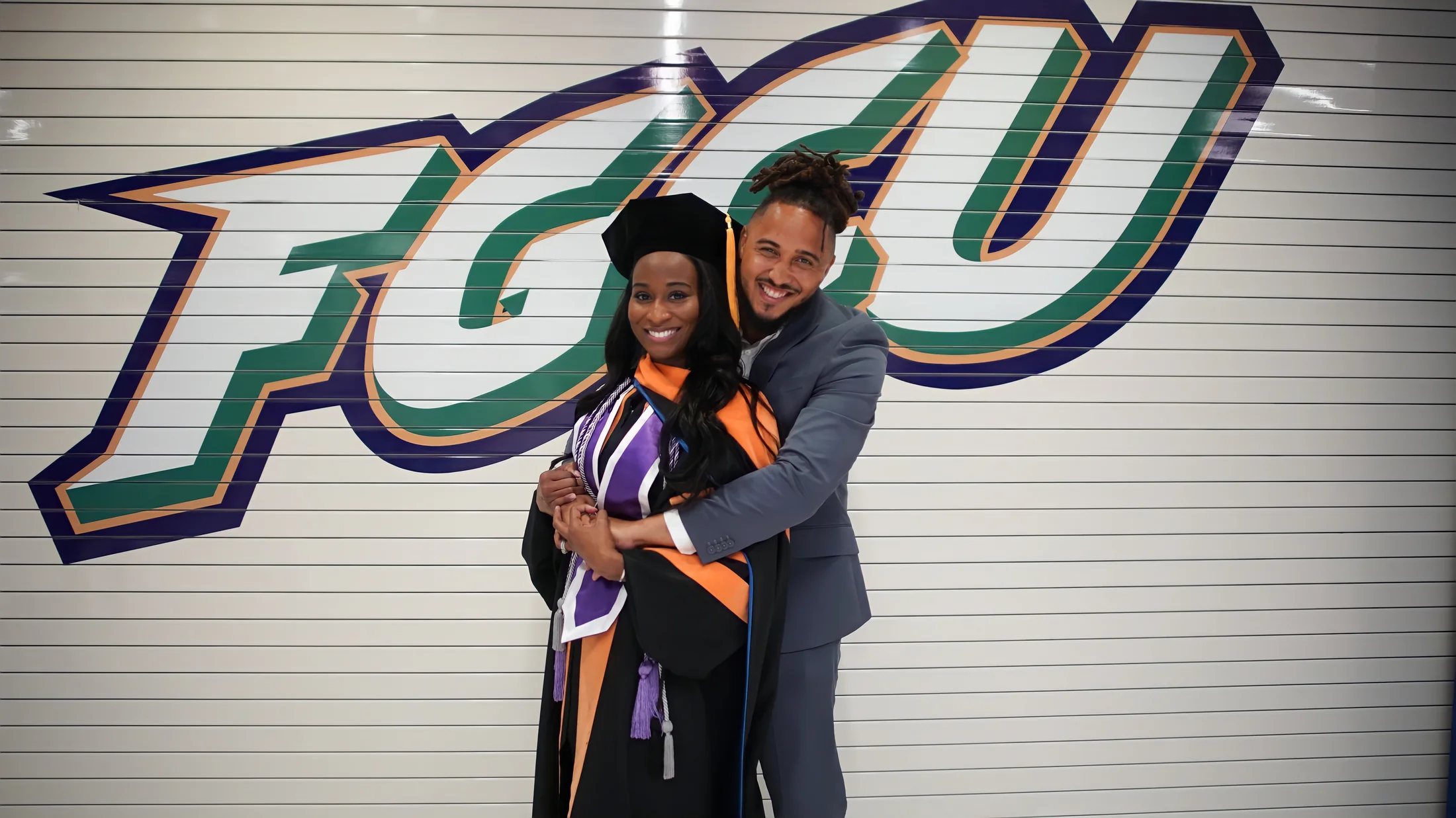 Ronnie Lillard embraces Christine in her doctoral regalia at Florida Gulf Coast University