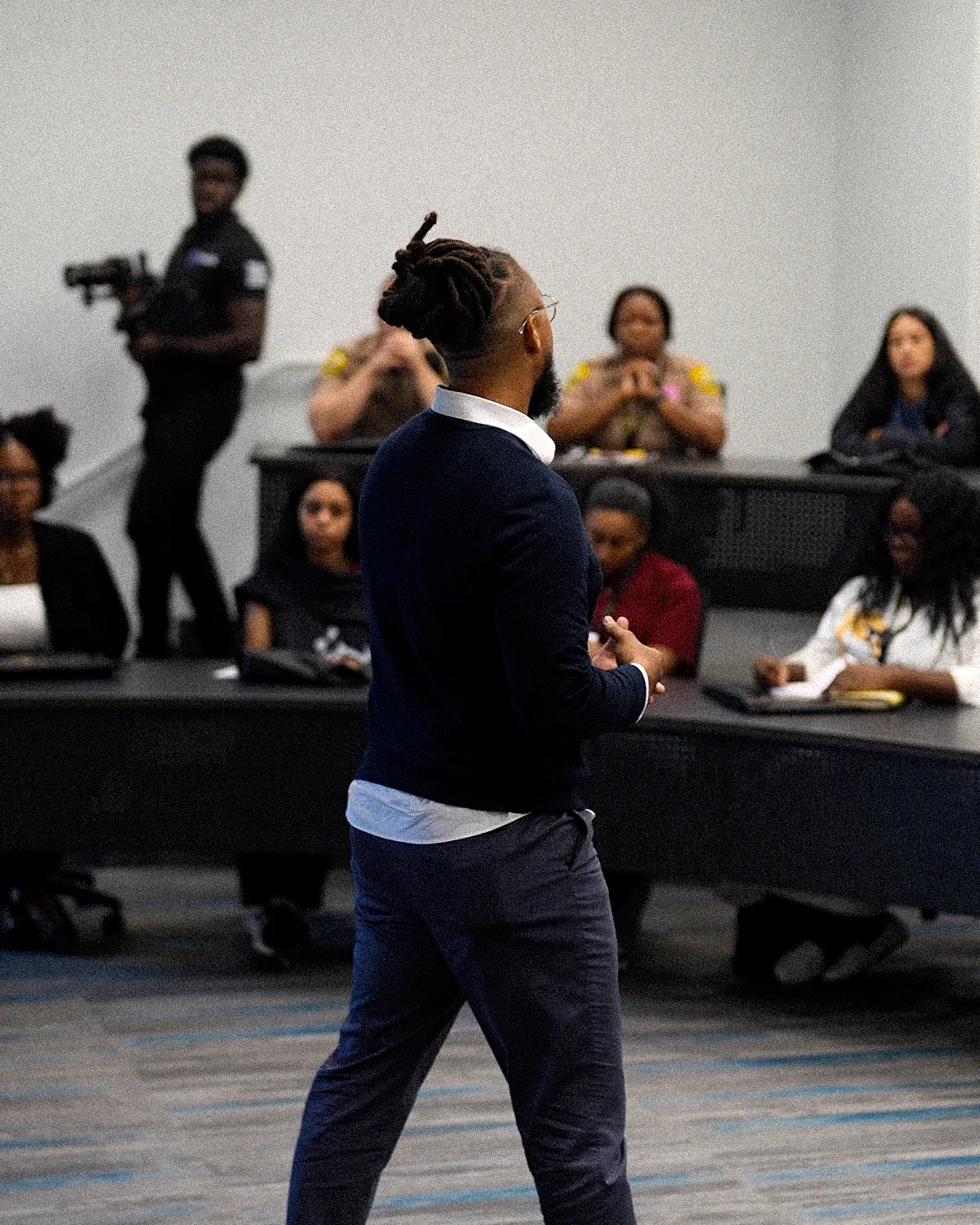Ronnie Lillard teaching a lecture room of students and officers at St. Thomas University while a camera operator films