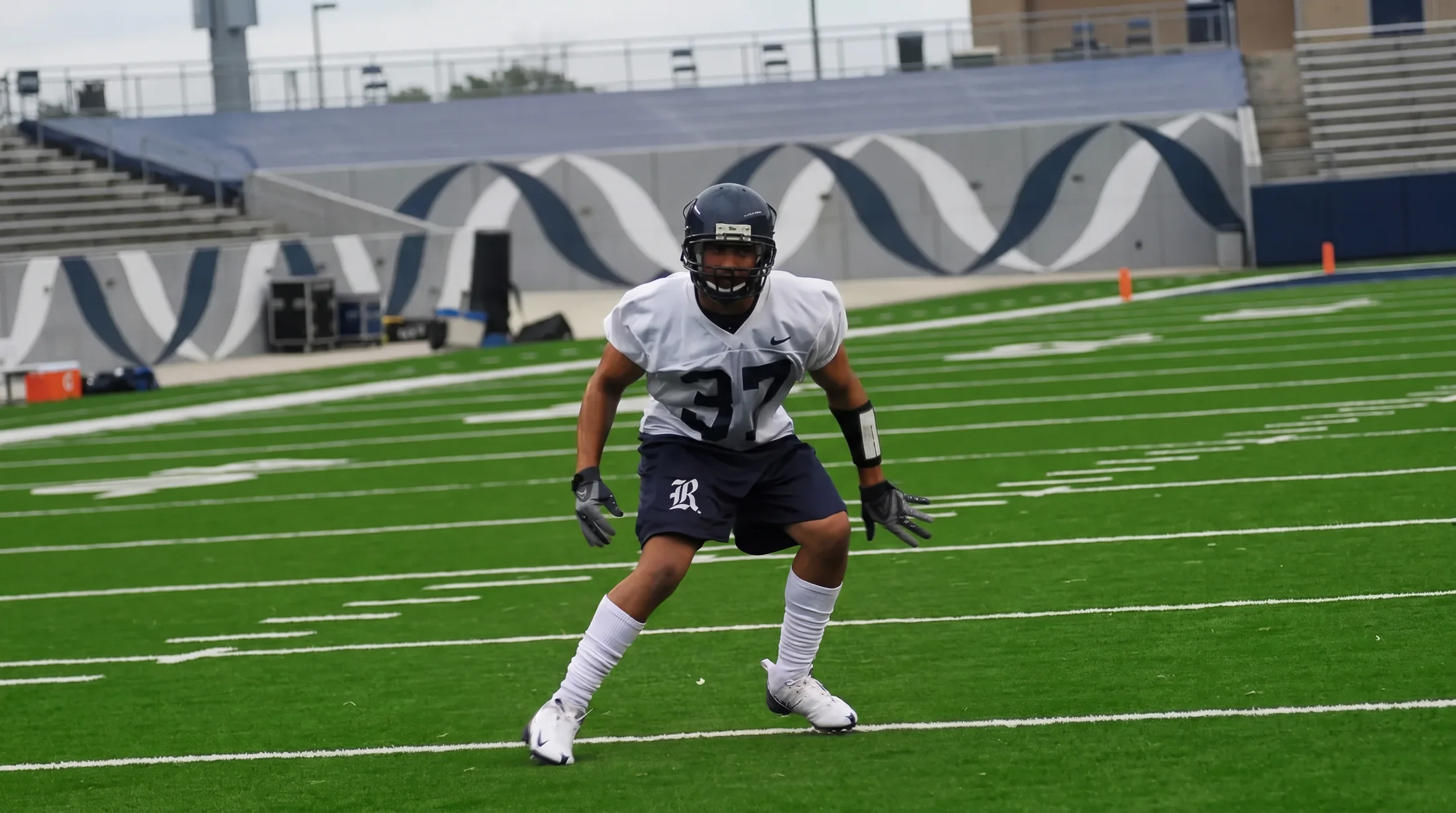Ronnie Lillard in a white Rice practice jersey, number 37, in a defensive stance on the field