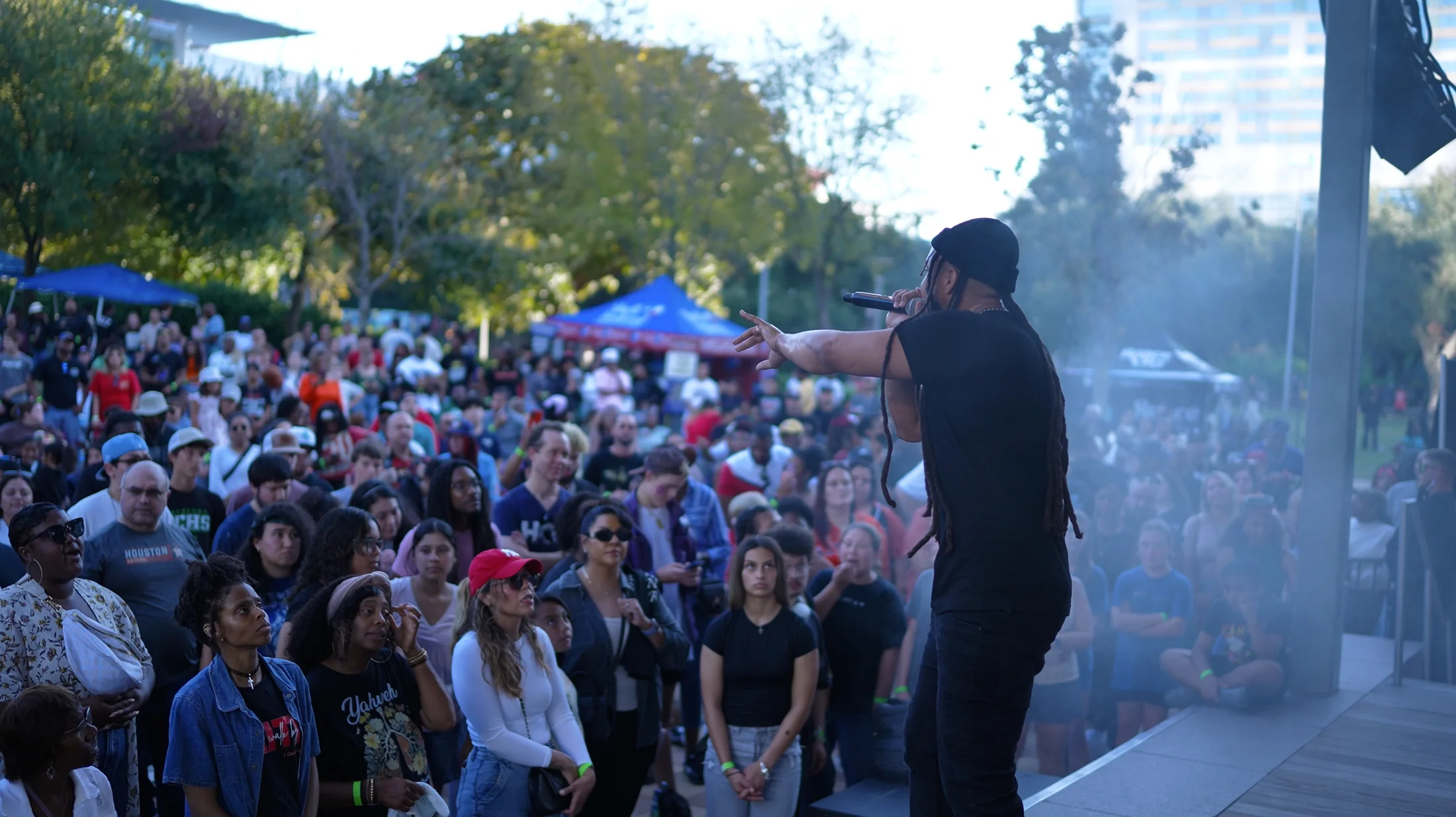 Reconcile performs on an outdoor stage, reaching toward a large crowd in downtown Houston