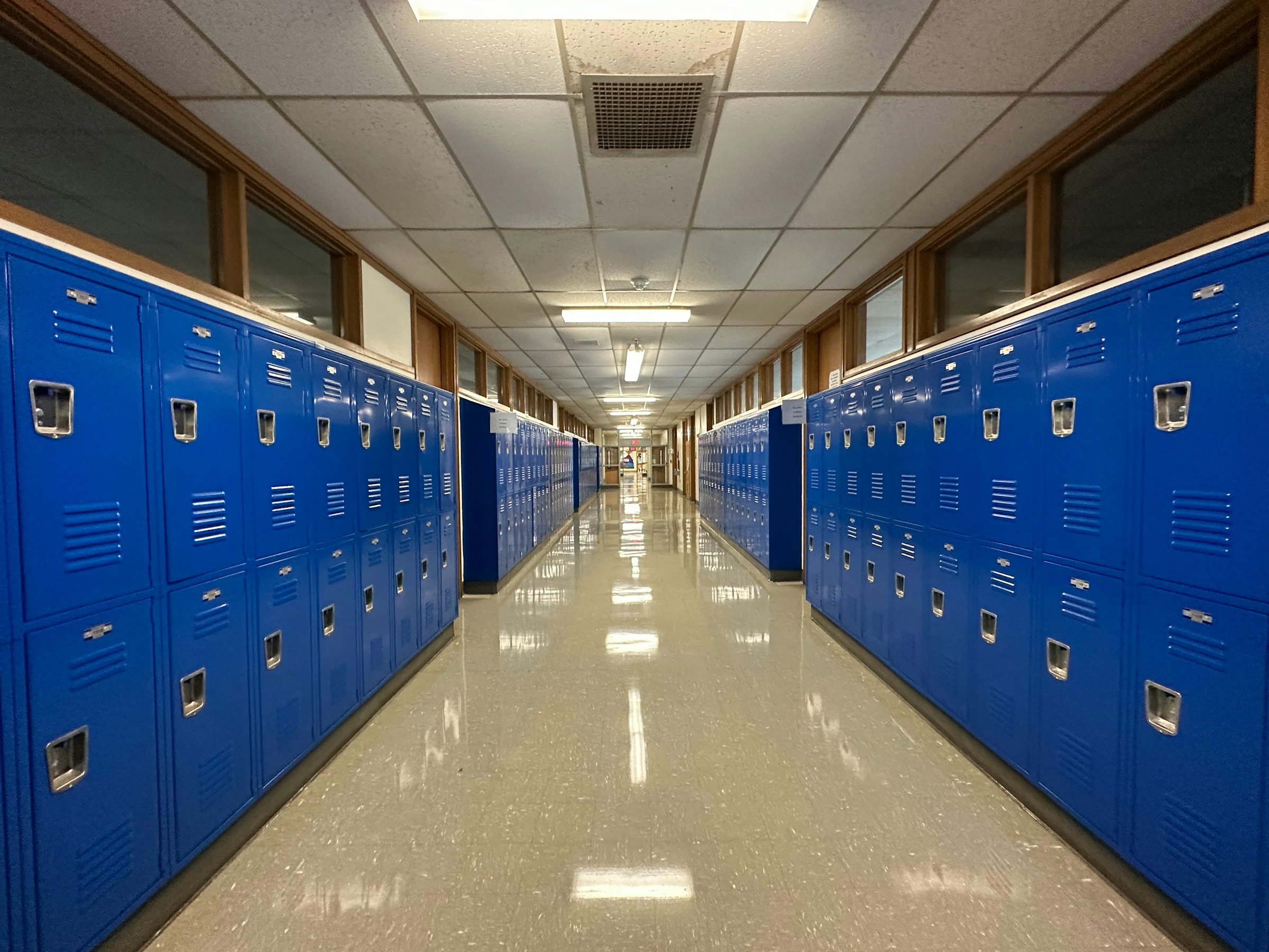 An empty middle school hallway lined with lockers after classes have ended.